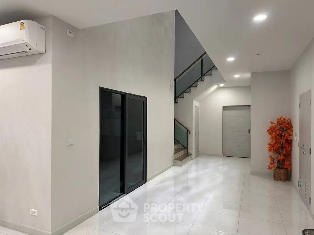 Modern interior with sleek staircase and air conditioning in spacious hallway.
