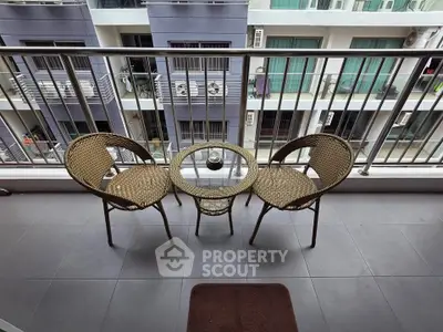 Charming balcony with cozy seating overlooking modern building facade.