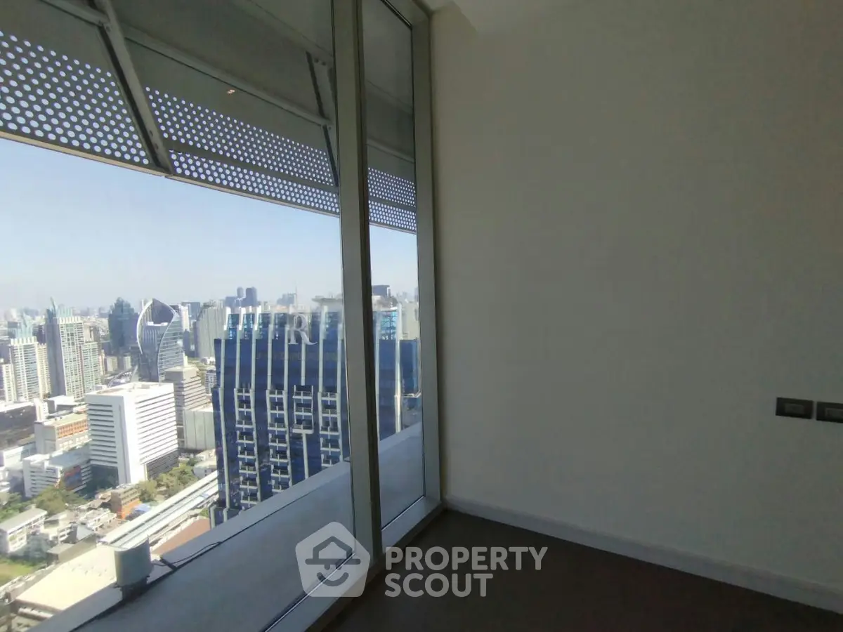 Stunning city view from high-rise apartment with floor-to-ceiling windows.