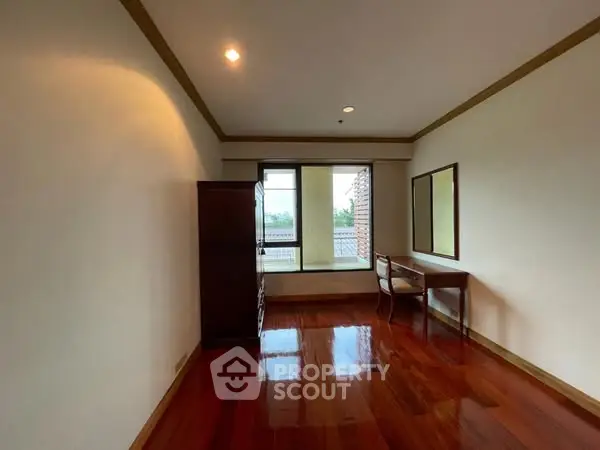 Spacious room with polished wooden floors and large window view