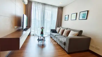 Modern living room with sleek furniture and large window offering natural light.