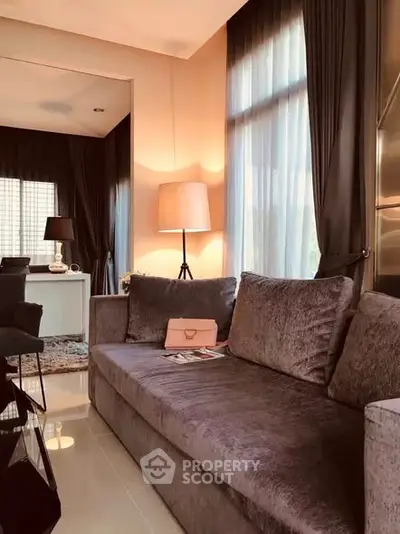 Elegant living room with plush sofa and stylish decor, bathed in natural light through large windows.
