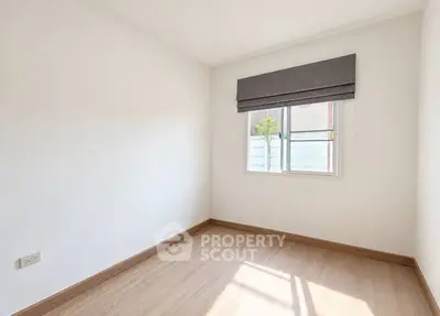 Bright empty room with wooden flooring and large window, perfect for customization.