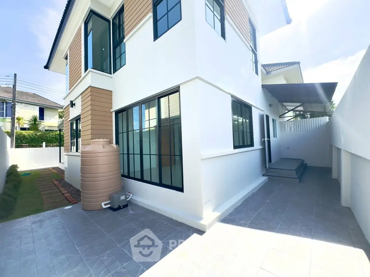 Modern two-story house with large windows and outdoor space, perfect for family living.
