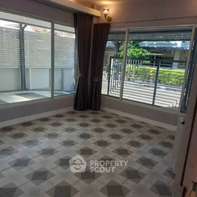 Spacious corner unit with large windows and patterned tile flooring, offering ample natural light and garden views.