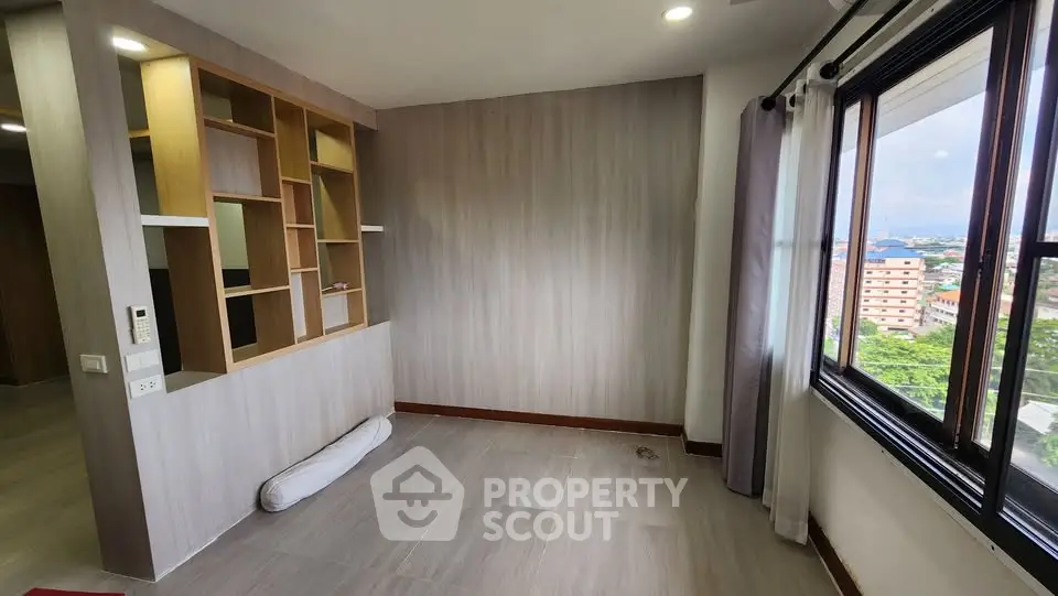 Spacious room with large window and built-in shelving, offering a bright and airy atmosphere.