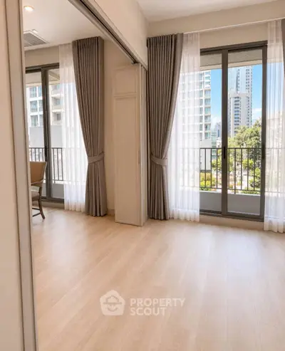 Spacious apartment with large windows and city view, featuring elegant curtains and wooden flooring.