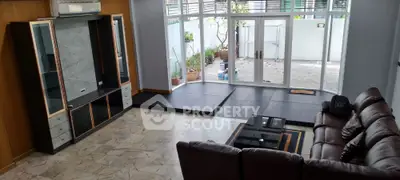 Spacious living room with leather sofa and large windows opening to patio