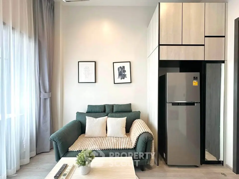 Modern living room with stylish sofa and sleek kitchen area featuring a stainless steel fridge.