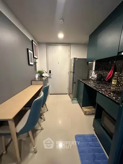 Modern kitchen with sleek cabinetry and dining area in compact apartment