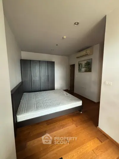 Spacious bedroom with wooden flooring and modern wardrobe in a stylish apartment.