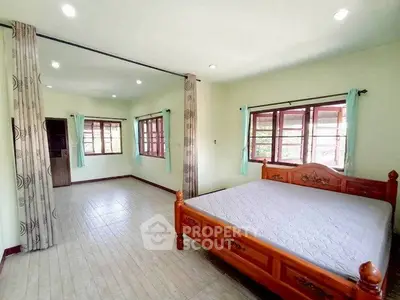 Spacious bedroom with wooden bed and large windows offering natural light.