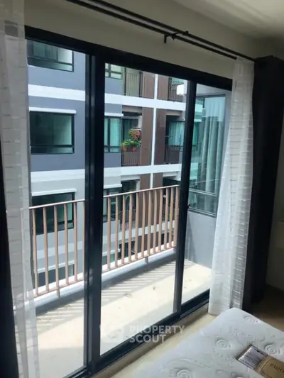 Modern apartment bedroom with balcony view and large sliding glass doors.