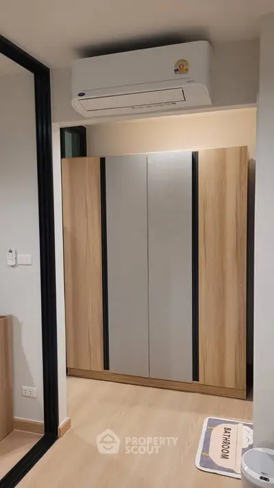 Modern bedroom with sleek wardrobe and air conditioning unit, perfect for comfortable living.