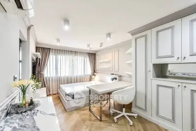 Modern bedroom with study area, featuring elegant cabinetry and natural light, perfect for urban living.