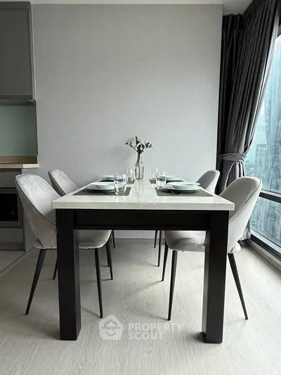 Modern dining area with elegant table and chairs, large window view, and minimalist decor.