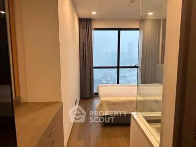 Modern bedroom with city view, featuring sleek design and large window for natural light.