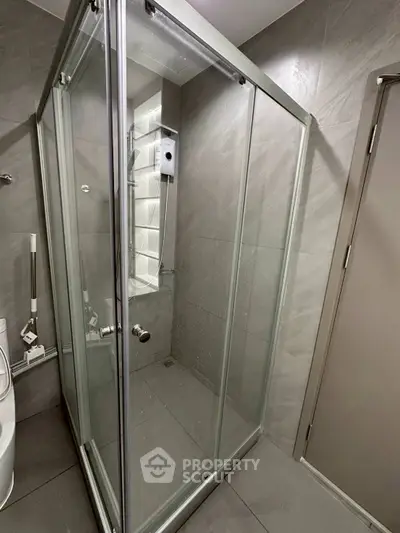 Modern bathroom with sleek glass shower enclosure and gray tile design.