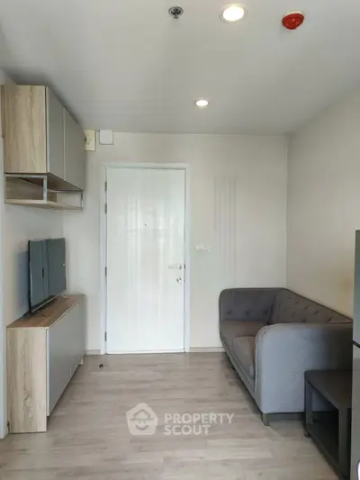 Modern living room with sleek furniture and minimalist design, featuring a cozy gray sofa and mounted TV.