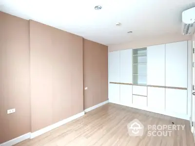 Spacious empty room with built-in storage and wooden flooring