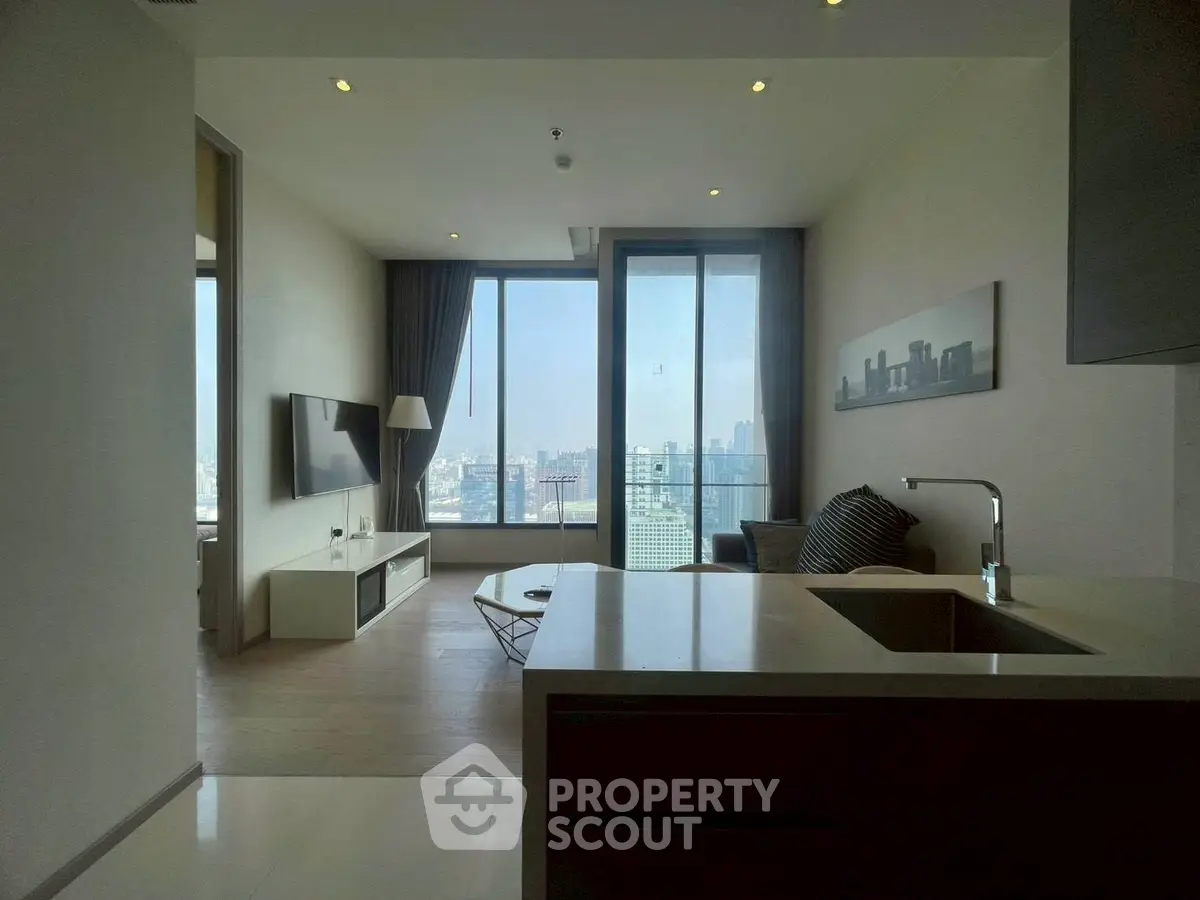Modern living room with city view, sleek furniture, and large windows in a high-rise apartment.