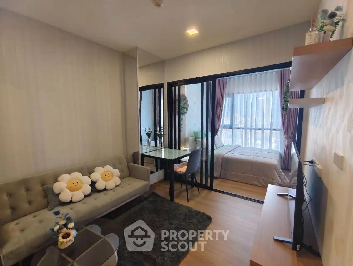Modern studio apartment with cozy living area and bedroom separated by glass doors, featuring stylish decor.
