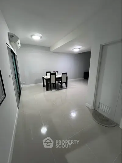 Spacious dining area with modern furniture and sleek tile flooring in a contemporary apartment.