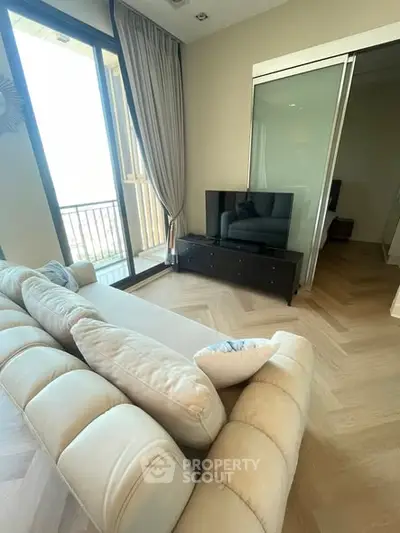 Spacious living room with modern decor and balcony access, featuring a plush sofa and sleek TV setup.