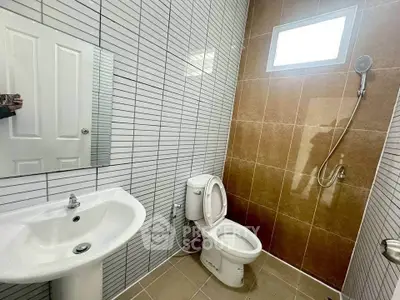 Modern bathroom with sleek tiles, white fixtures, and a walk-in shower.