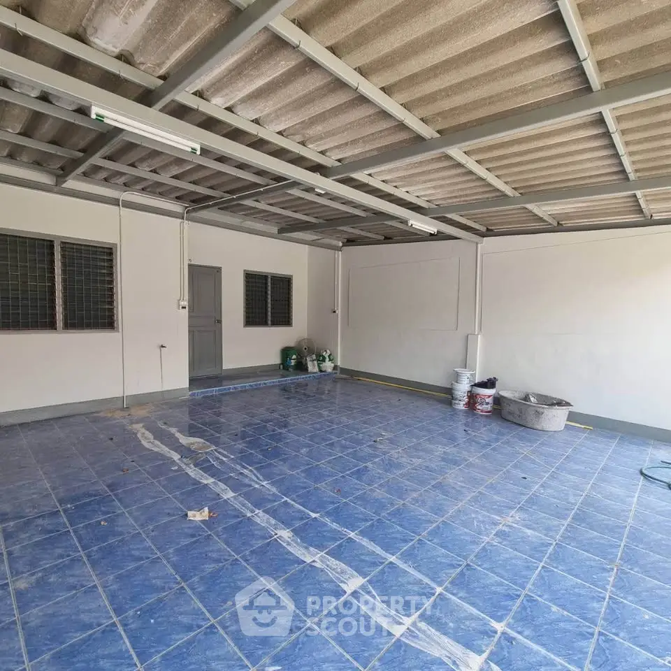 Spacious tiled garage with metal roofing and storage potential, ideal for vehicle parking or workshop setup.