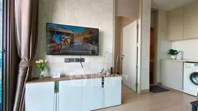 Modern living room with TV, stylish cabinet, and washing machine in open layout apartment.