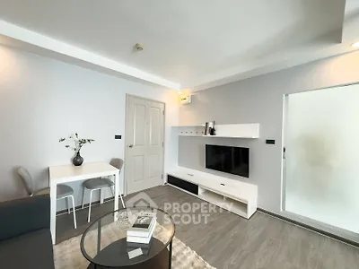 Modern living room with sleek furniture and minimalist decor, featuring a wall-mounted TV and cozy seating area.