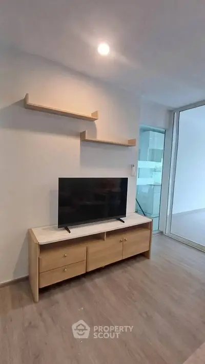 Modern living room with sleek TV stand and floating shelves, featuring minimalist design and natural light.