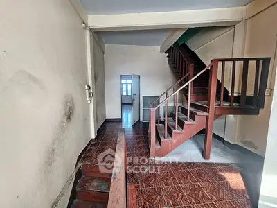 Spacious interior with wooden staircase and tiled flooring, ideal for renovation.