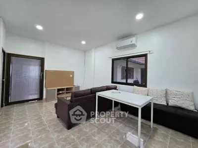 Spacious living room with modern furniture and air conditioning in a bright, tiled interior.