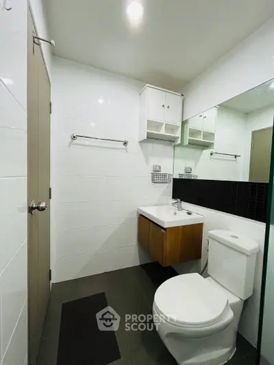 Modern bathroom with sleek fixtures and minimalist design, featuring a wall-mounted sink and spacious mirror.