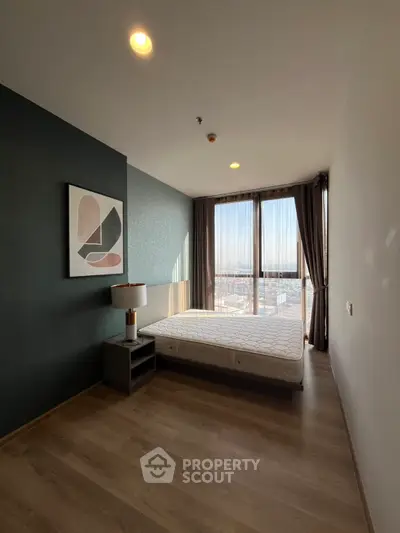 Modern bedroom with large window and stylish decor in high-rise apartment.