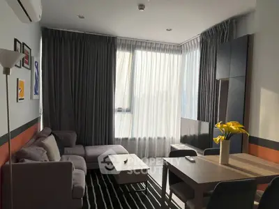 Modern living room with cozy sofa, stylish decor, and ample natural light from large windows.