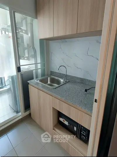 Modern compact kitchen with sleek cabinetry and granite countertop in a stylish apartment.