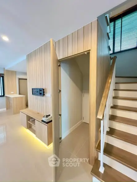 Modern interior with sleek staircase and wood paneling, showcasing contemporary design and open space.