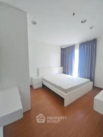 Spacious bedroom with modern minimalist design and large window for natural light.