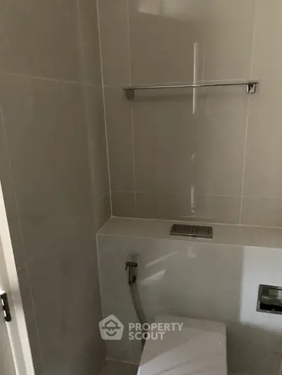 Modern minimalist bathroom with sleek tile design and concealed cistern.