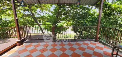 Charming outdoor terrace with vibrant checkered flooring and lush greenery view.
