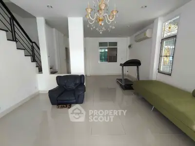 Spacious living room with modern chandelier and fitness equipment, perfect for relaxation and exercise.