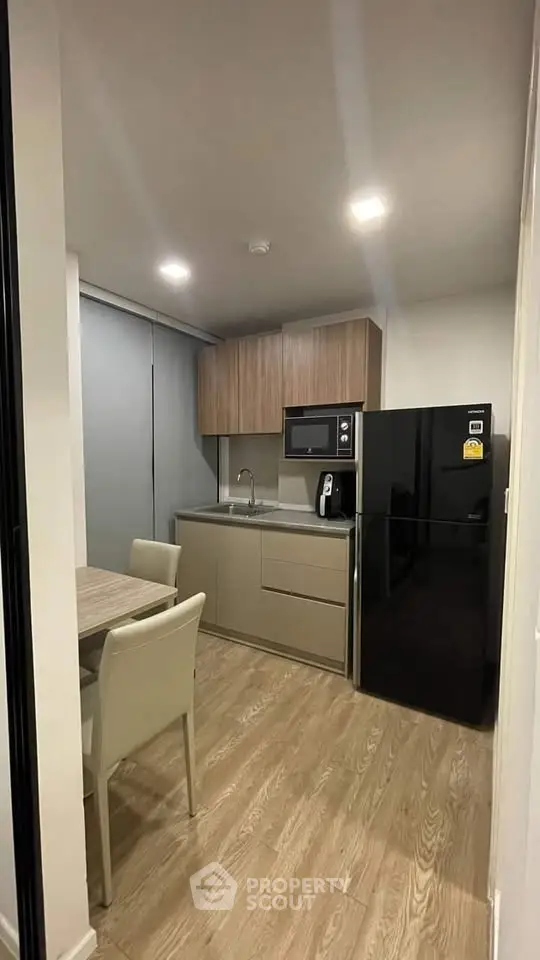Modern kitchen with sleek cabinetry and dining area in cozy apartment.