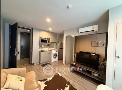 Modern living room with open kitchen, featuring washing machine and air conditioning.