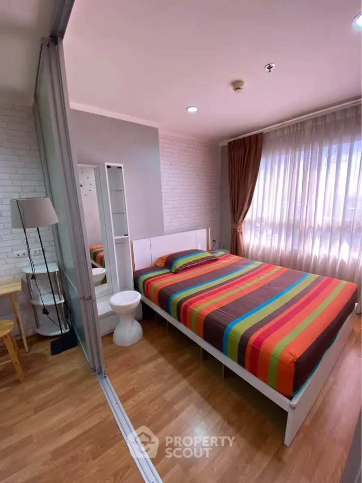 Cozy bedroom with colorful bedding and large window for natural light