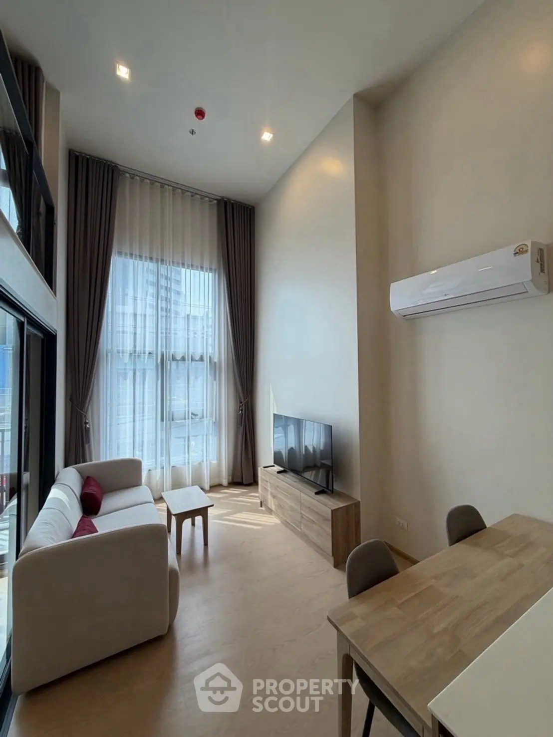 Modern living room with high ceiling and large windows in a stylish apartment.