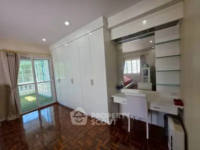Spacious bedroom with elegant parquet flooring and built-in wardrobe, featuring a cozy vanity area.