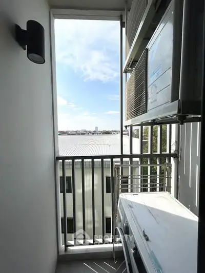 Compact balcony with air conditioning unit and city view, ideal for urban living.